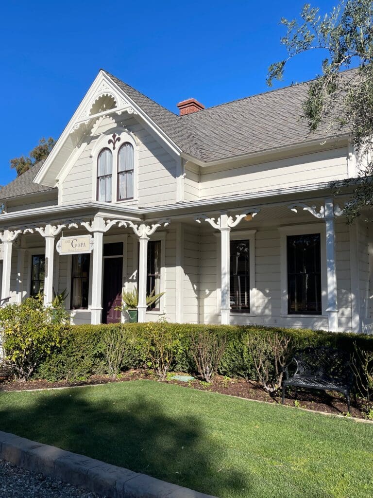 A white house with a large porch and a lawn.