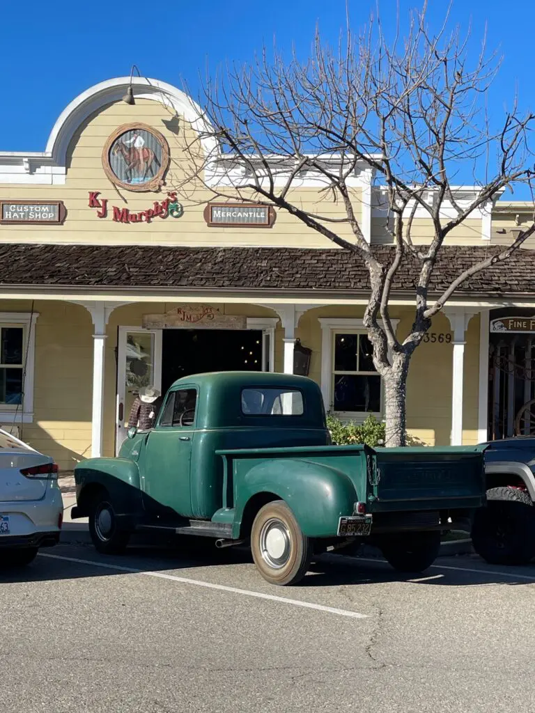 A green truck parked in front of a building.