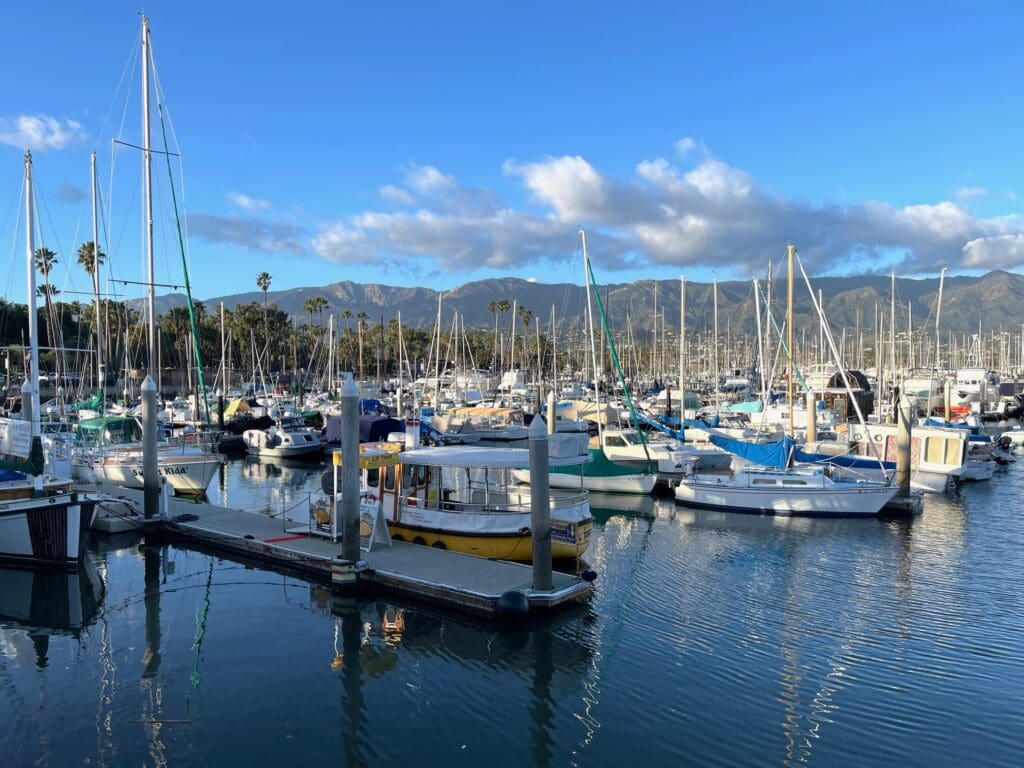 A group of boats in the water near some mountains.